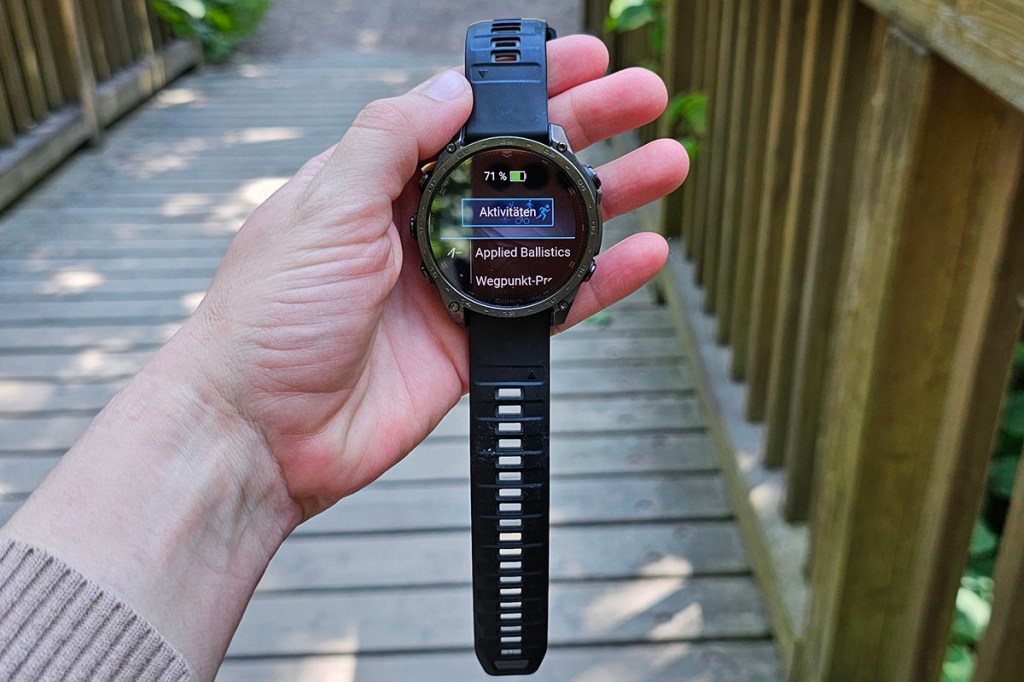 Hand hält Smartwatch auf einer Brücke