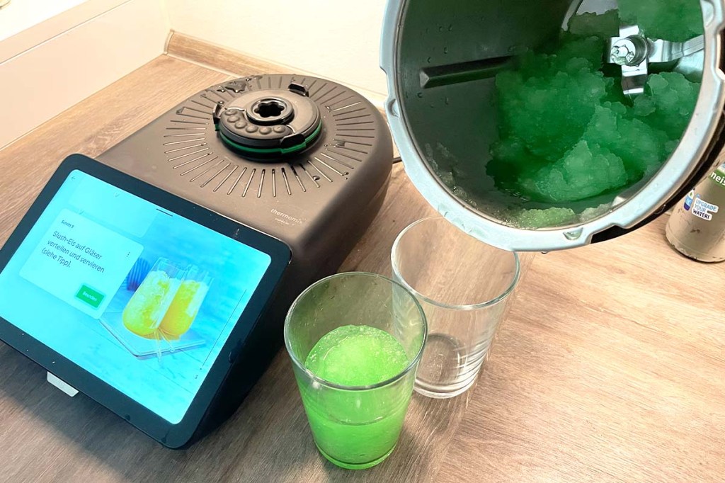 Eine Person füllt grünes Slush Eis aus dem Mixtopf des TM7 in zwei Gläser um.